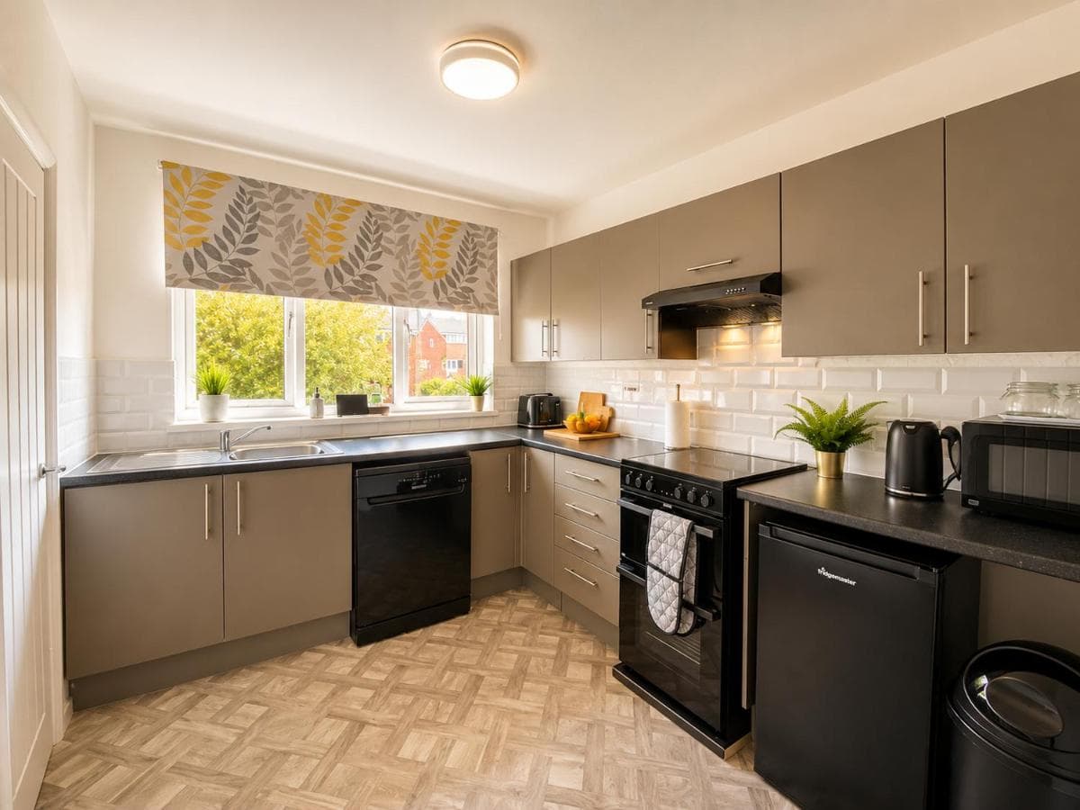 Fully equipped kitchen with black appliances at Caistor Apartment